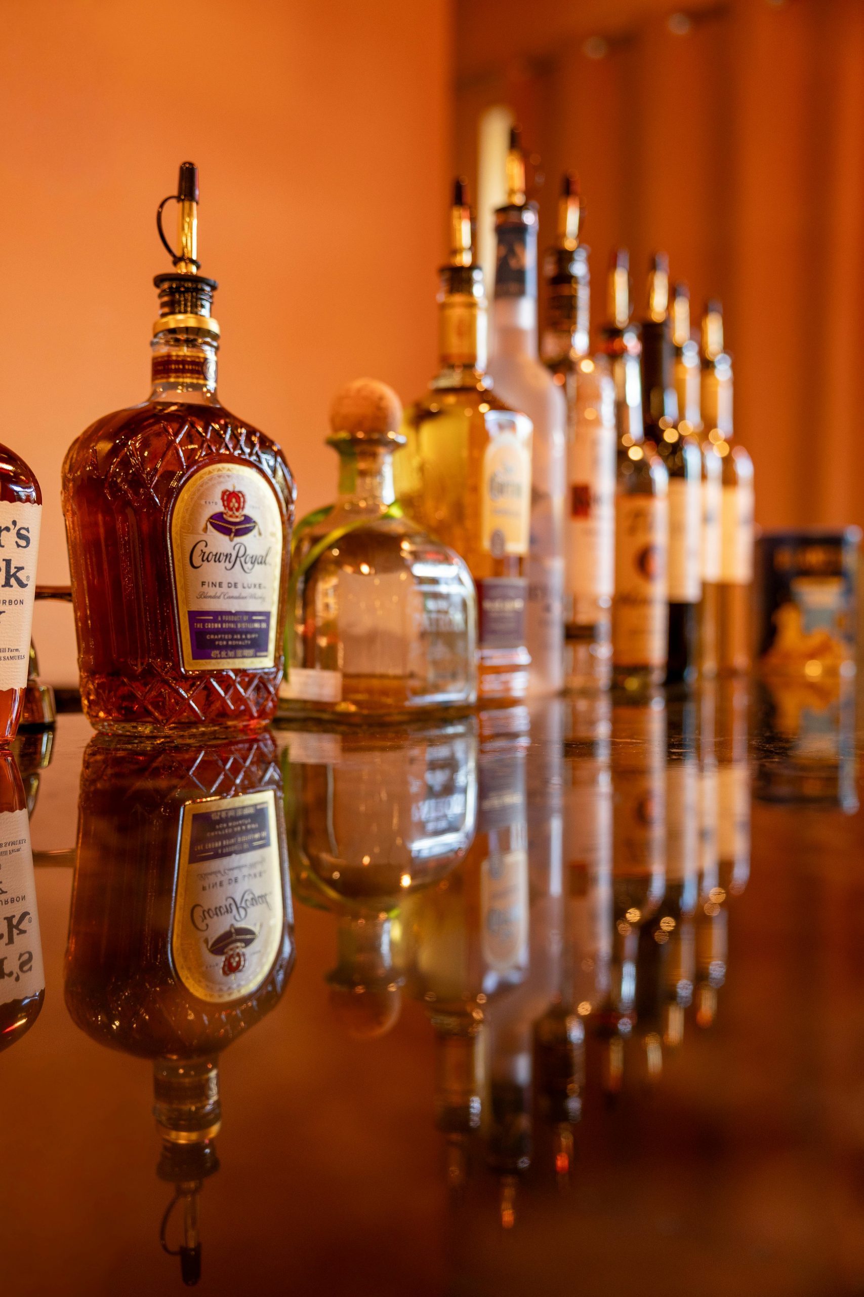 A collection of premium alcoholic beverages displayed on a reflective bar surface, creating a luxurious ambiance.